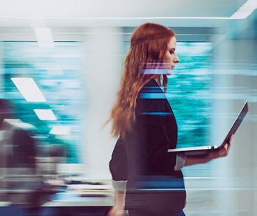 Businesswoman holding a laptop walking