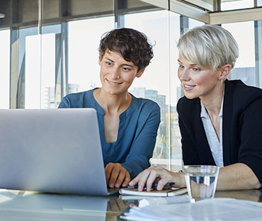 Businesswomen sharing laptop